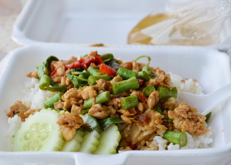 spicy stir fried chicken with basil leaf on rice in foam box for take home