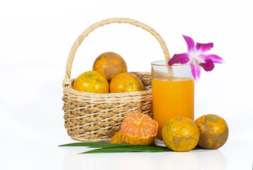 Glass of orange juice with oranges in basket