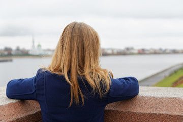 girl looks at the embankment of the river in the fall