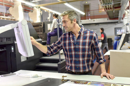 Man working on printing machine in print factory