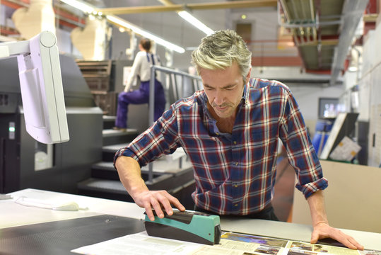 Man working on printing machine in print factory