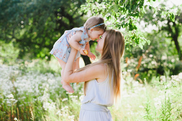 Young mother playing with her little daughter on the nature, motherhood, tenderness, childhood,...
