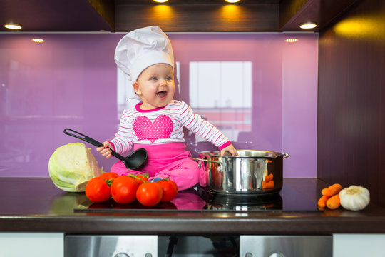 Little baby girl cook in chef hat at the kitchen