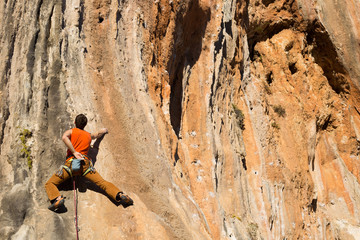 Young male climber hanging by a cliff.