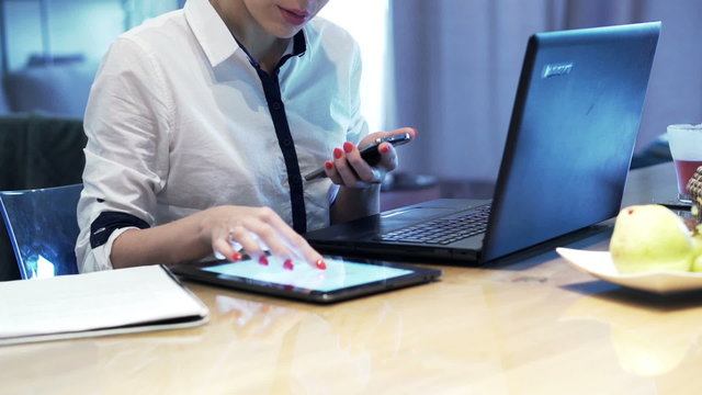 Busy, multitasking businesswoman working by table at home
