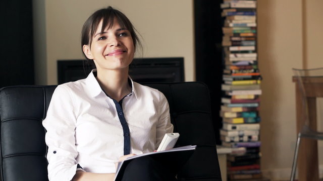 Happy businesswoman watching TV sitting on chair at home
