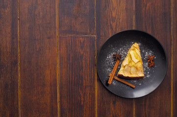 Apple pie on the plate with cinnamon sticks