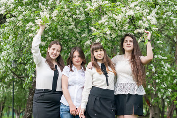four girls graduate walk in the lush spring garden after school