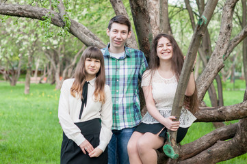 Three young friends happy graduates smiling in the summer park