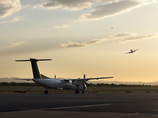 Fototapeta na wymiar Turboprop auf dem Vorfeld mit startendem Jet im Hintergrund