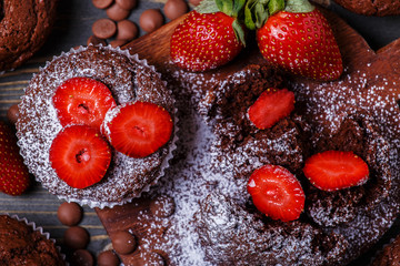 Chocolate muffins with strawberry on dark background.