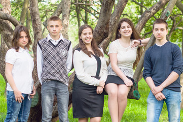 Five happy friends posing in the summer park