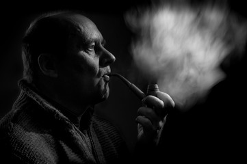 Fototapeta premium Black and white portrait of a caucasian man smoking tobacco pipe