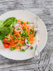 Fresh carrots, radishes, spinach and green peas salad. Healthy food. On light rustic wooden background