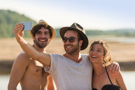 In Summer, three friends taking selfies at the beach during the holidays
