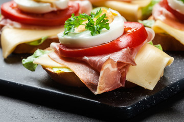 Delicious sandwich with prosciutto ham, cheese, tomato and egg