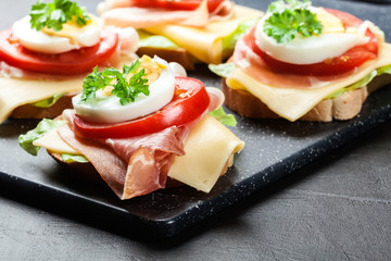 Delicious sandwich with prosciutto ham, cheese, tomato and egg