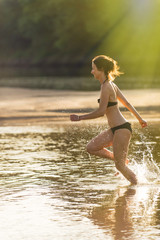 woman is running in the water at the beach in summertime