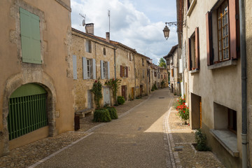 typical French narrow street with ocher colored facades of old houses in small village in Aquitaine 