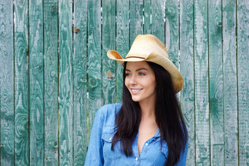 Attractive young brunette woman smiling with cowboy hat