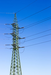 a high voltage power pylons against blue sky and sun rays