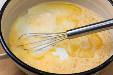 Mixed eggs with yogurt in the bowl with wire