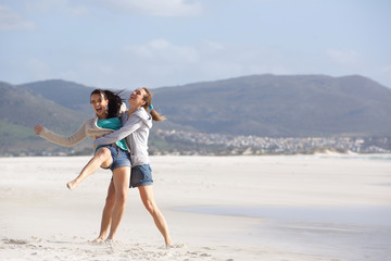 Two playful girlfriends having a good time at the beach