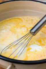 Mixed eggs with yogurt in the bowl with wire