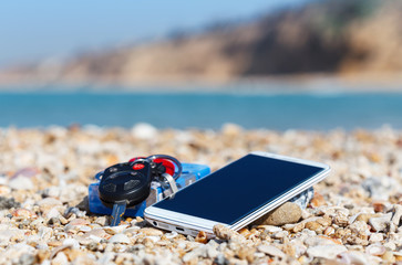Fototapeta na wymiar Vacation time, smart phone, car keys and cigarettes, on the seashells in the beach
