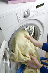 Using washing machine , woman takes washed laundry from the washing machine