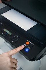 Woman switching on start button of laser printer