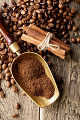 ground coffee in scoop and coffee beans on a wooden background