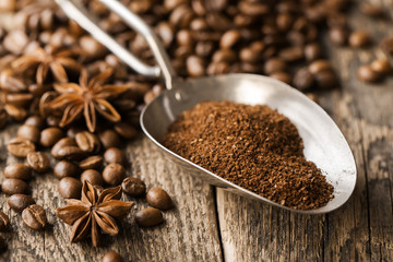 ground coffee in scoop and coffee beans on a wooden background