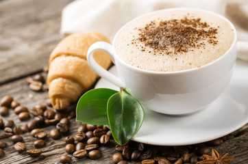 Close-up of coffee cup with roasted coffee beans on wooden backg