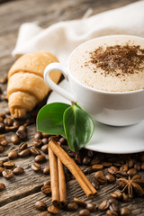 Close-up of coffee cup with roasted coffee beans on wooden backg