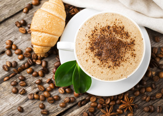 Close-up of coffee cup with roasted coffee beans on wooden backg