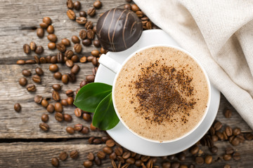 Close-up of coffee cup with roasted coffee beans on wooden backg