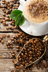 Close-up of coffee cup with roasted coffee beans on wooden backg