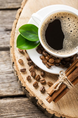 Close-up of coffee cup with roasted coffee beans on wooden backg