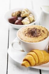 Hot cappuccino and pastries on white wooden boards