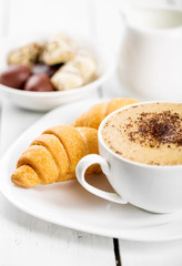 Hot cappuccino and pastries on white wooden boards