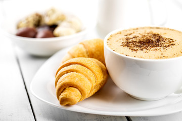 Hot cappuccino and pastries on white wooden boards