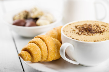 Hot cappuccino and pastries on white wooden boards