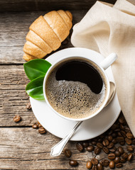 Close-up of coffee cup with roasted coffee beans on wooden backg