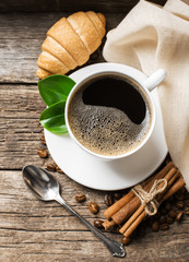Close-up of coffee cup with roasted coffee beans on wooden backg