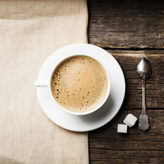 Close-up of coffee cup with roasted coffee beans on wooden backg