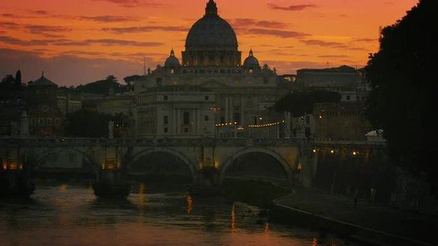 Slight tilt up and pan of Ponte Sant'Angelo and St. Peter's Basilica at dusk
