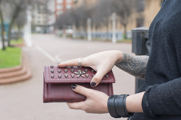 Hands with tattoo open wallet in the street.