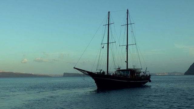 Pleasure craft stylized ancient ship departs from the wharf, Therasia, Greece.
