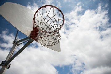 basket ball hoop outside against a blue sky with clouds